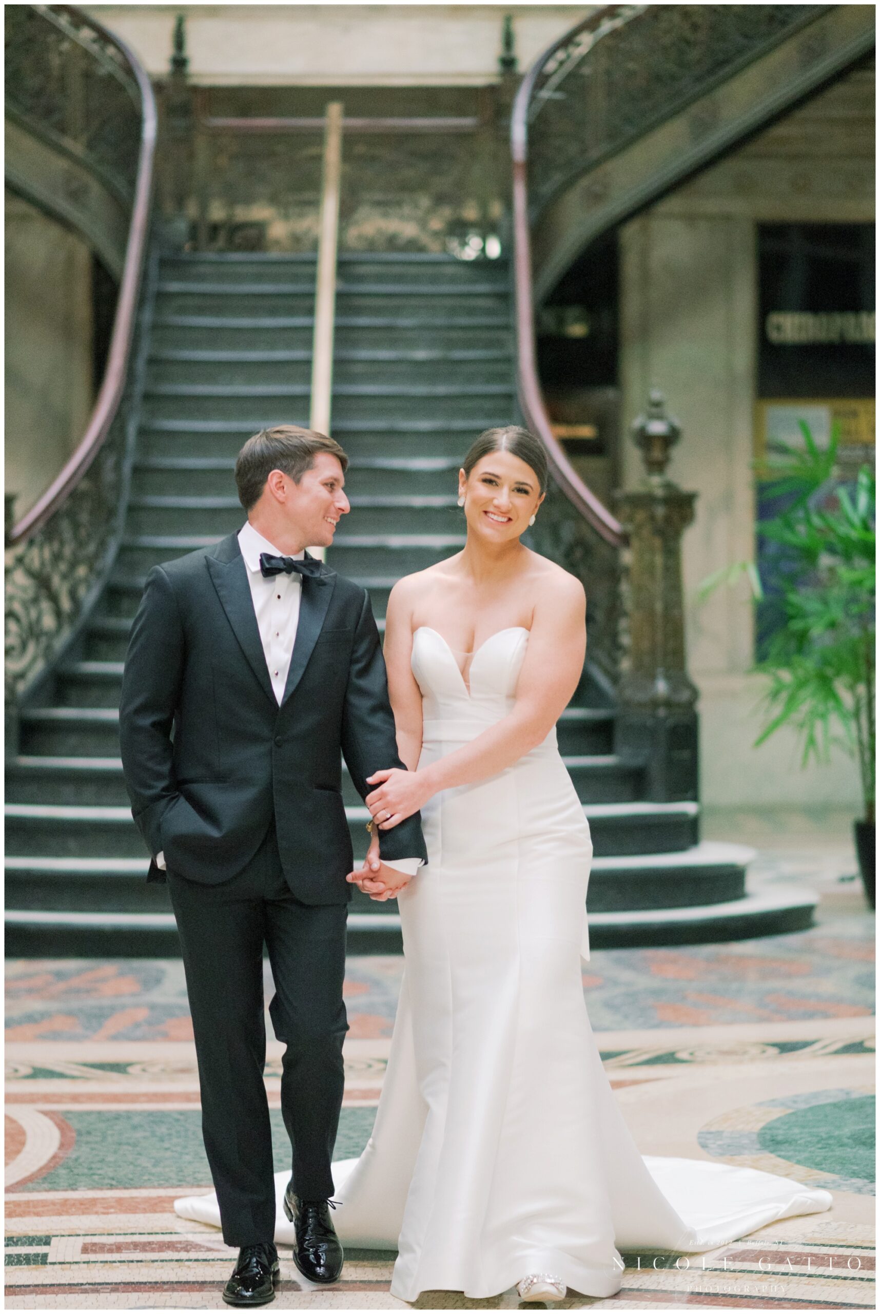 bride smiling at camera with from walking bride and groom from wedding at the eliicott square building buffalo ny