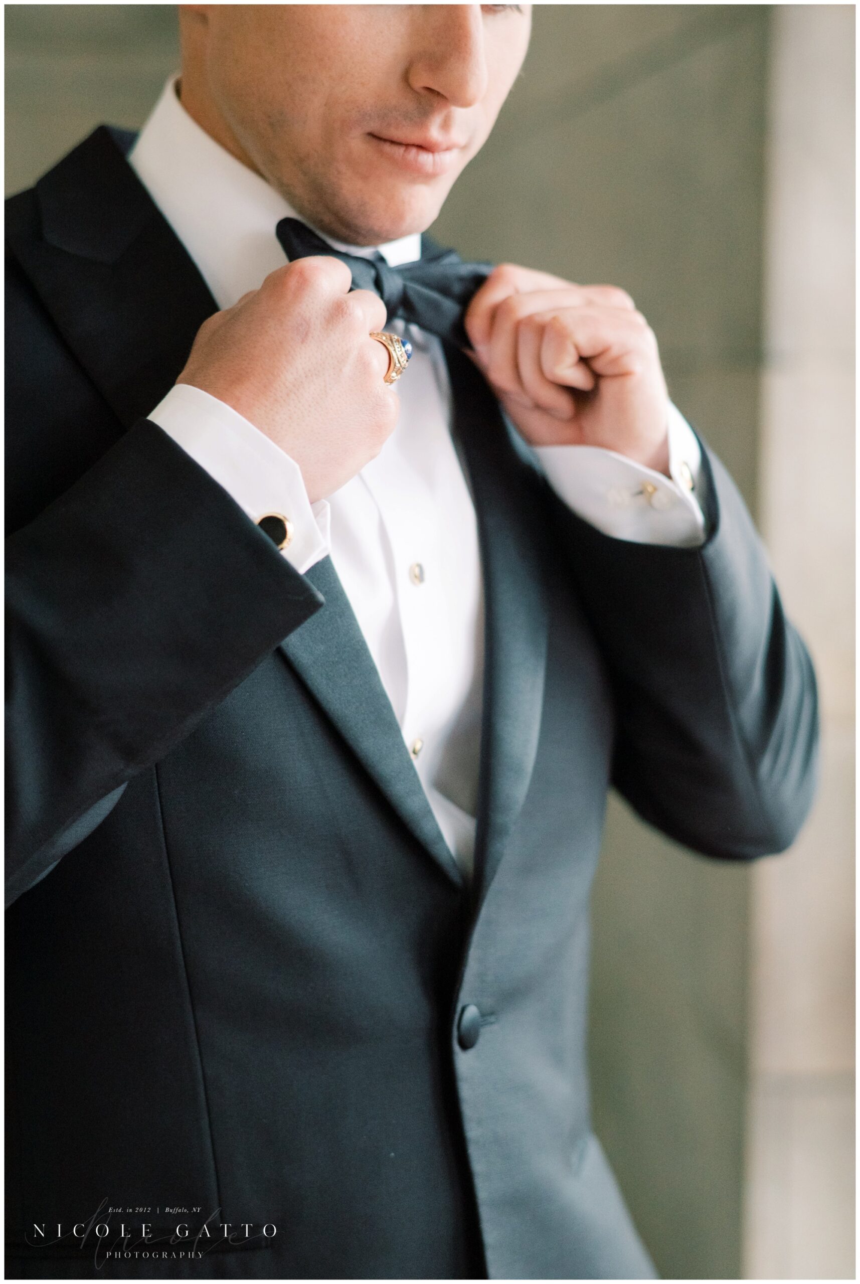 detail of groom adjusting bowtie at ellicott square building