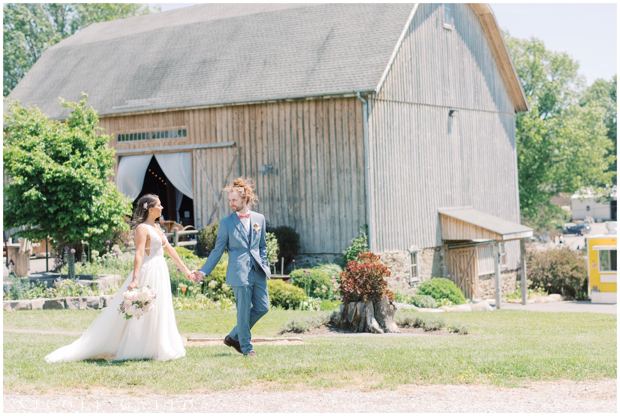 bride and groom walking in front of wedding at hayloft in the grove