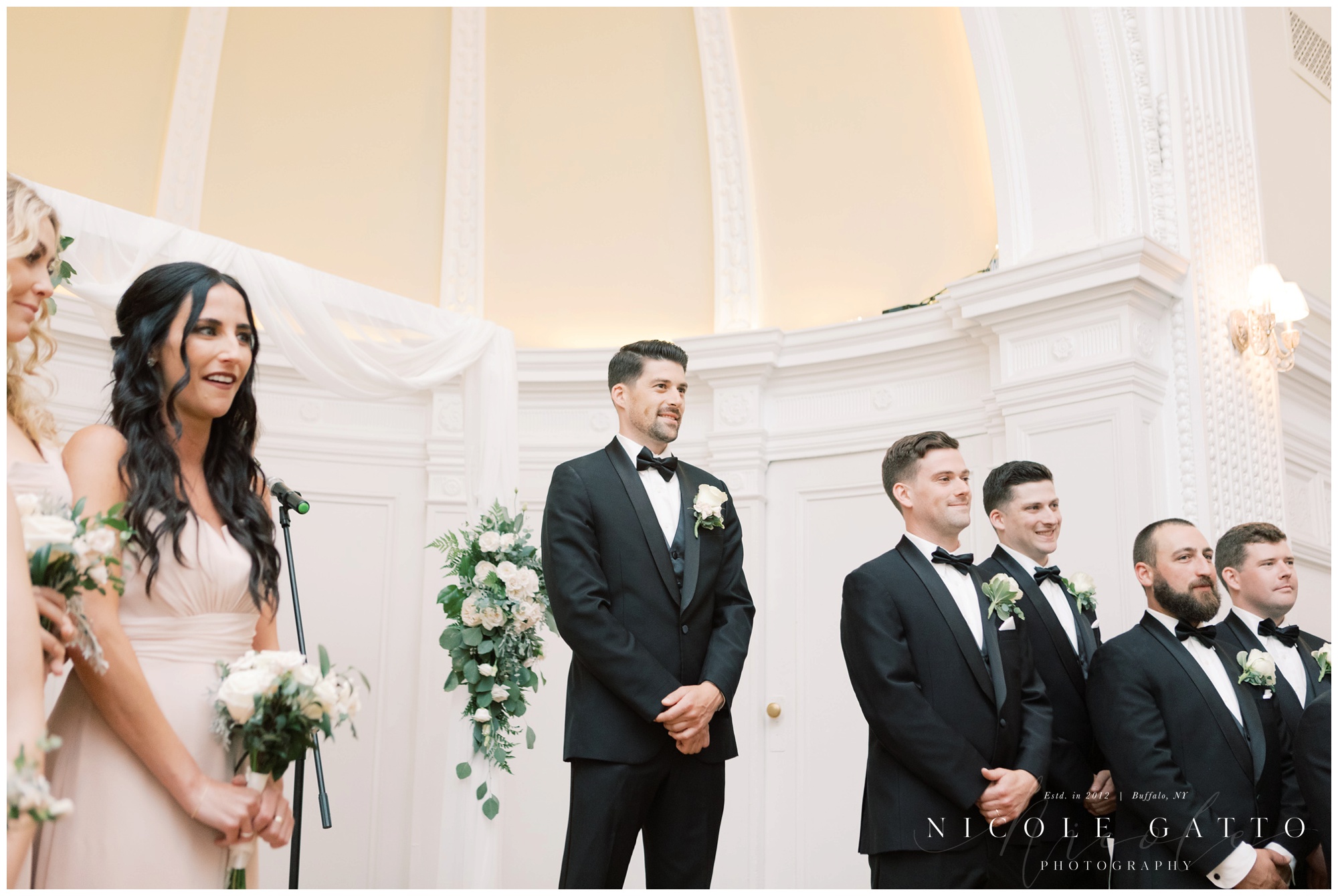 groom smiling at bride as she walks down aisle